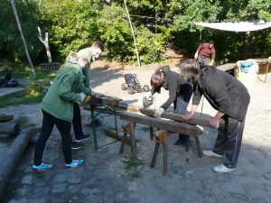 Team von Mitarbeitern bearbeiten Holzstämme für den Schweinestall