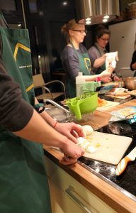 Mitarbeiter schneidet Käse während dem Teamevent Kochen.