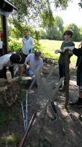 Mitarbeiter unterstützt während Teambuilding Kinder beim Sägen